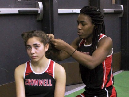 FILE - In this Feb. 7, 2019 file photo, Cromwell High School transgender athlete Andraya Yearwood, right, braids the hair of teammate Taylor Santos during a break at a track meet at Hillhouse High School in New Haven, Conn. The federal Office for Civil Rights has launched an investigation into …