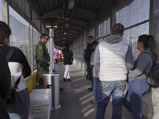A Border Patrol agent, back left, and a U.S. Customs and Border Protection agent, right, o