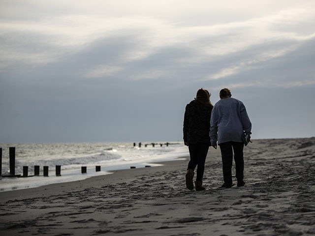 People walk on the beach in Cape May, N.J., Wednesday, March 18, 2020. Some people who liv