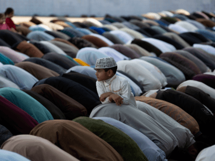 A Pakistani boy stands amid of people offer Friday prayers besides government's advice to