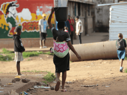 In this Monday, April 6, 2020 photo, a woman carries a her baby and a bucket of water in H