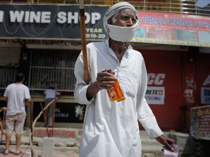 An elderly Indian man walks with two bottles of liquor purchased from one of the liquor shops which was reopened Monday after six weeks lockdown on the outskirts of New Delhi, India, Monday, May 4, 2020. India's six-week coronavirus lockdown, which was supposed to end on Monday, has been extended …