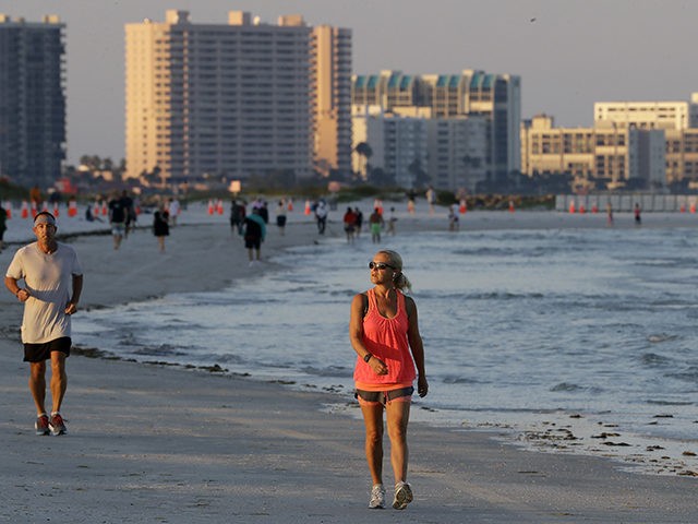 People run and walk along Clearwater Beach after it was reopened to the public Monday, May 4, 2020, in Clearwater Beach, Fla. Many public beaches and restaurants are reopening as part of Florida Gov. Ron DeSantis' phase one to stop the spread of the coronavirus. (AP Photo/Chris O'Meara)