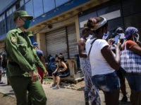 People wearing masks as a precaution against the spread of the new coronavirus talk to each other while waiting in front of a store to buy food in Havana, Cuba, Tuesday, May 19, 2020. Cuban authorities are requiring the use of masks for anyone outside their homes . (AP Photo …