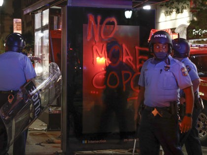 Philadelphia police patrol the streets near a bus stop with graffitti after the Justice fo