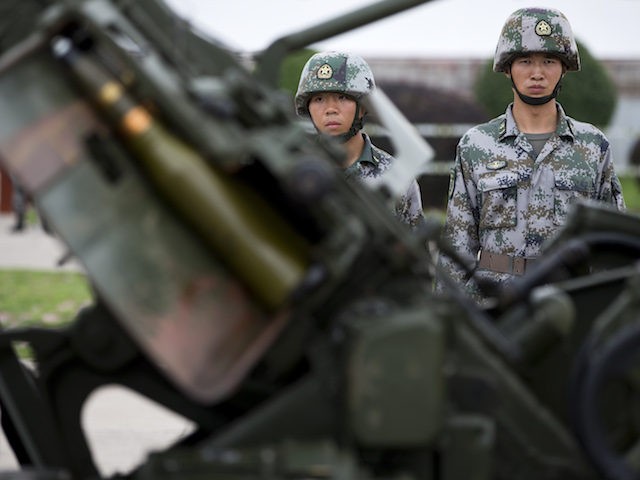 Soldiers stand near the PG59 57mm anti-aircraft artillery gun after conducting a demonstration at a base of People’s Liberation Army Lanzhou Military 47th Combined Corps anti-air brigade in Xi'an in northwest China's Shaanxi province Monday, July 29, 2013. (AP Photo/Andy Wong)