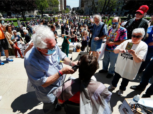 Barber Karl Manke, of Owosso, gives a free haircut on the steps of the State Capitol during a rally in Lansing, Mich., Wednesday, May 20, 2020. Barbers and hair stylists are protesting the state's stay-at-home orders, a defiant demonstration that reflects how salons have become a symbol for small businesses …