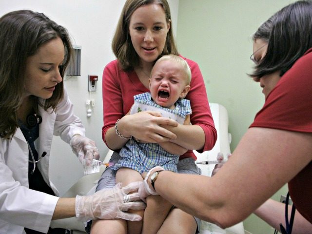 Duncan Barnes, 1, is held by his mother, Jennifer Barnes, while receiving a vaccine for sw