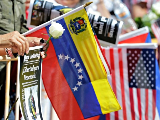 A woman holds a white rose and a sign reading Freedom for Venezuela, at a rally to commemo