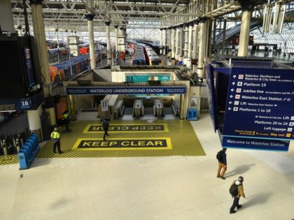 Travellers pass a new "Keep Clear" floor sign, to encourage social distancing, a