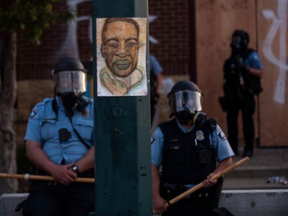 MINNEAPOLIS, MN - MAY 27: A portrait of George Floyd hangs on a street light pole as police officers stand guard at the Third Police Precinct during a face off with a group of protesters on May 27, 2020 in Minneapolis, Minnesota. The station has become the site of an …