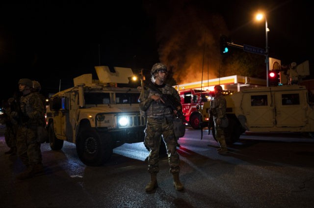 MINNEAPOLIS, MN - MAY 29: Members of the National Guard hold a perimeter as a fire crew works to put out a fire at a gas station on Lake Street on May 29, 2020 in Minneapolis, Minnesota. Protests have been ongoing in the state and around the country since George …