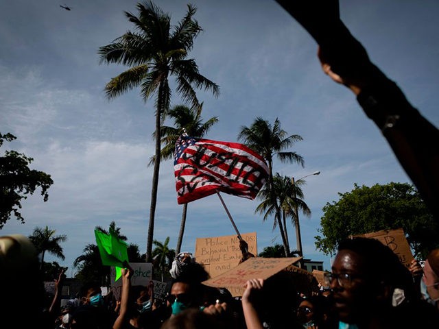 Protestors wave a US flag with the word Justice painted on it as they gather at Fort Laude