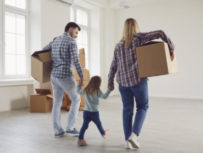 Happy family with children moving with boxes in a new apartment house. Relocation concept new house apartment rental housing.