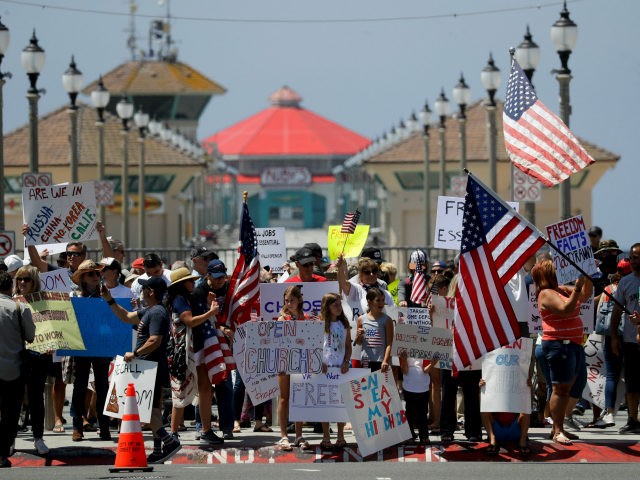 Law enforcement personnel on horseback keep protestors on the sidewalk during a May Day demonstration at the pier Friday, May 1, 2020, in Huntington Beach, Calif. (AP Photo/Chris Carlson)