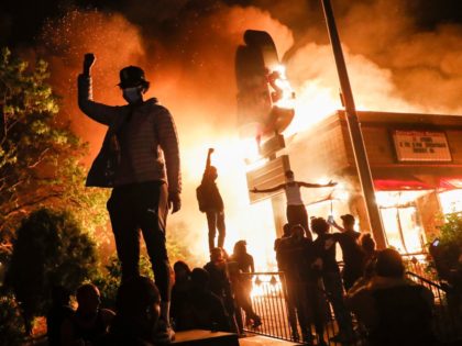 Protestors demonstrate outside of a burning fast food restaurant, Friday, May 29, 2020, in