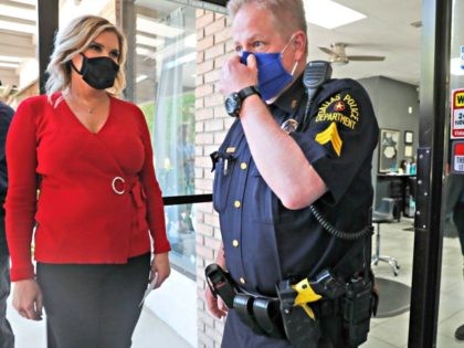 Amid concerns of the spread of COVID-19, salon owner Shelley Luther, left, holds the door open a Dallas police officer to leave the business after city officials cited her for reopening her Salon A la Mode in Dallas, Friday, April 24, 2020. Hair salons have not been cleared for reopening …