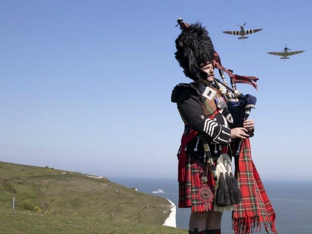 Pipe major Andy Reid of The Scots Guards plays his pipes on the cliffs of Dover, Kent, as two Spitfires from the Battle of Britain memorial flight fly overhead, ahead of commemorations to mark the 75th anniversary of VE Day Friday May 8, 2020. (Richard Pohle/The Times via AP)