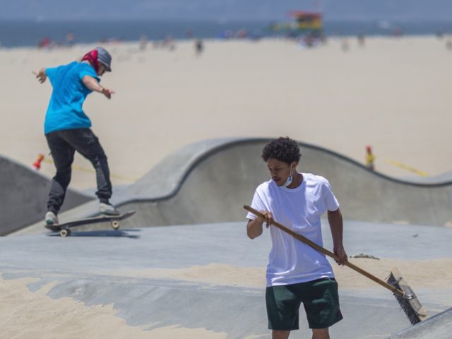 LOS ANGELES, CA - MAY 24: Skateboarders remove sand that was dumped into a skate park to k