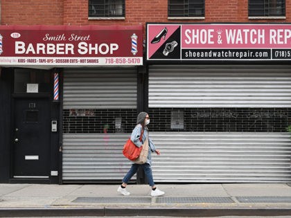 A woman walks by a closed barber shop and shoe and watch repair store on May 5, 2020 in the Brooklyn borough of New York City. (Photo by Angela Weiss / AFP) (Photo by ANGELA WEISS/AFP via Getty Images)