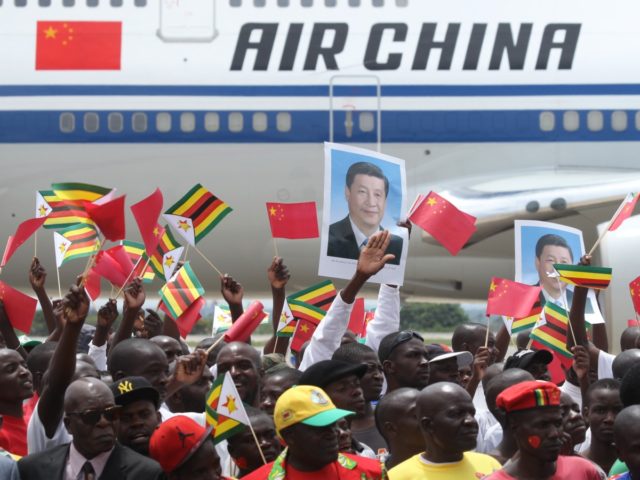 Zimbabweans wave flags while welcoming Chinese President Xi Jinping in Harare, Zimbabwe, T