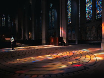 Empty church with stained glass windows and man walking