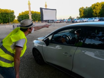 A staff member directs a spectator in his vehicle prior to the start of a drive-in movie s