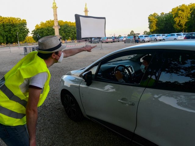 A staff member directs a spectator in his vehicle prior to the start of a drive-in movie screening on Place des Quinconces in Bordeaux, on May 16, 2020 as part of the Drive-in Festival featuring 10 movies in 10 days, while the cinemas in France are still closed due to …