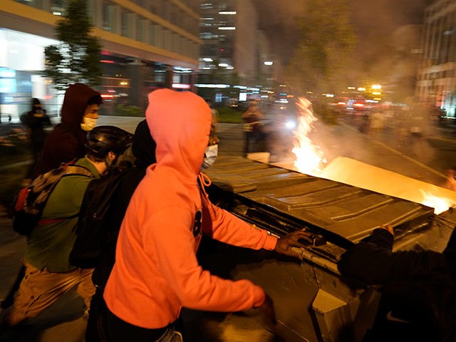 Demonstrators push a dumpster that is on fire towards a police line as people protest the death of George Floyd, Saturday, May 30, 2020, near the White House in Washington. Floyd died after being restrained by Minneapolis police officers. (AP Photo/Evan Vucci)