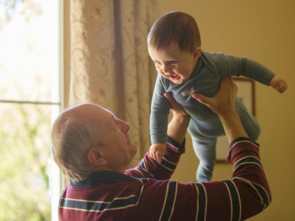 A grandfather holding his grandson in the air.
