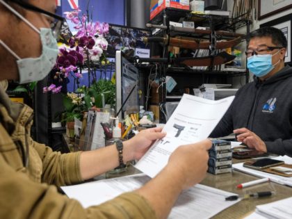 David Liu, right, owner of a gun store, takes an order from a customer in Arcadia, Calif., Sunday, March 15, 2020. Coronavirus concerns have led to consumer panic buying of grocery staples and now gun stores are seeing a run on weapons and ammunition as panic intensifies. (AP Photo/Ringo H.W. …