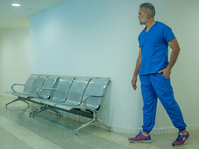 A healthcare worker looks into an empty waiting room.