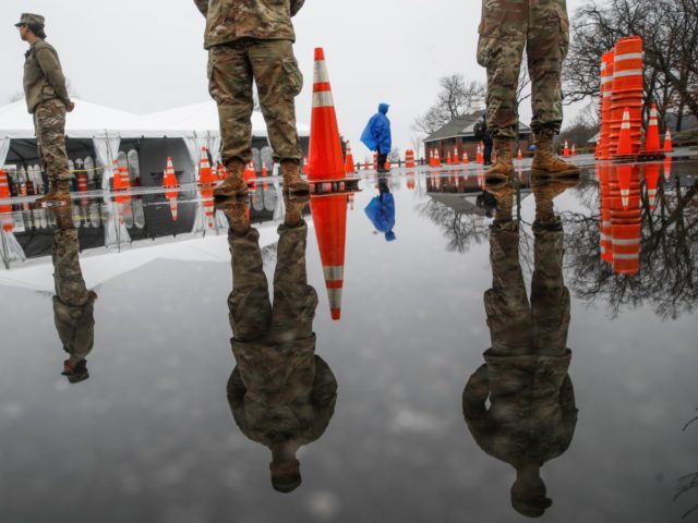 National Guard personnel stand at attention as they wait for patients to arrive for COVID-19 coronavirus testing facility at Glen Island Park, Friday, March 13, 2020, in New Rochelle, N.Y. State officials have set up a “containment area” in the New York City suburb, where schools and houses of worship …