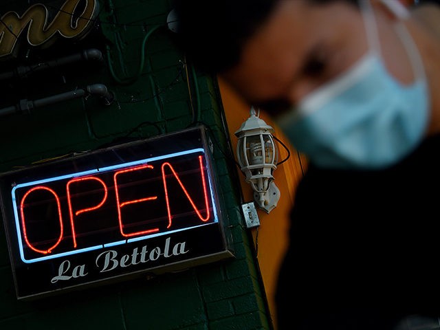 An employee cleans the entrance of a restaurant in the Crystal City neighborhood of Arling