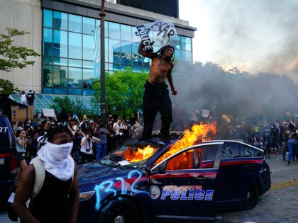 ATLANTA, GA - MAY 29: A man stands on top of a burning police car during a protest on May 29, 2020 in Atlanta, Georgia. Demonstrations are being held across the US after George Floyd died in police custody on May 25th in Minneapolis, Minnesota. (Photo by Elijah Nouvelage/Getty Images)