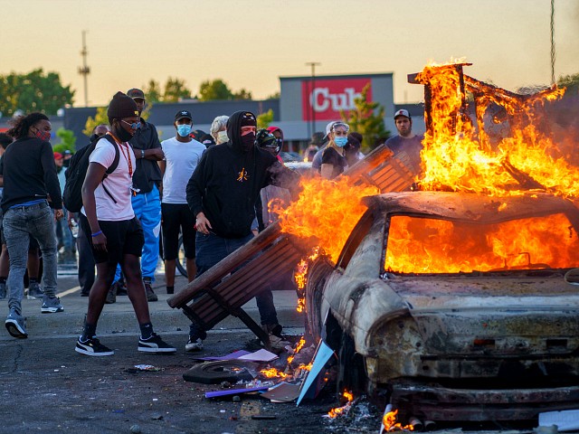 Protesters throw objects onto a burning car outside a Target store near the Third Police Precinct on May 28, 2020 in Minneapolis, Minnesota, during a demonstration over the death of George Floyd, an unarmed black man, who died after a police officer kneeled on his neck for several minutes. - Authorities in Minneapolis and its sister city St. Paul got reinforcements from the National Guard on May 28 as they girded for fresh protests and violence over the shocking police killing of a handcuffed black man. Three days after a policeman was filmed holding his knee to George Floyd's neck for more than five minutes until he went limp, outrage continued to spread over the latest example of police mistreatment of African Americans. protest (Photo by kerem yucel / AFP) (Photo by KEREM YUCEL/AFP via Getty Images)
