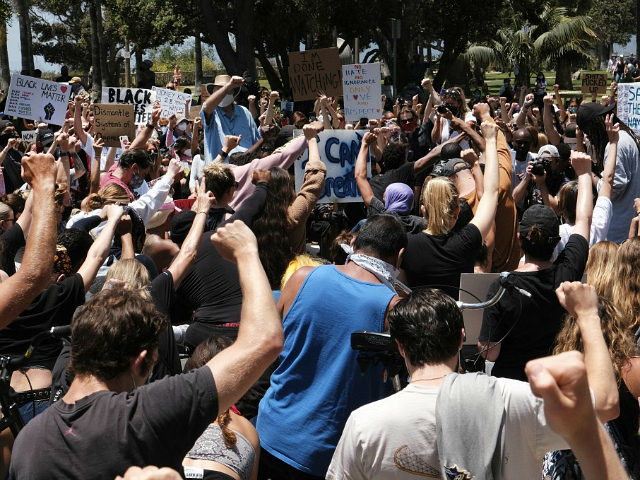 Protesters raise their fists and take to their knees in prayer during a Black Lives Matter