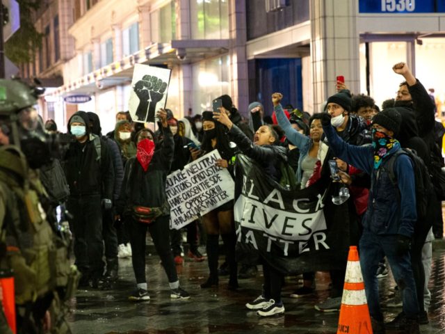 SEATTLE, WA - MAY 30: Protesters holding a Black Lives Matter banner shout at law enforcement officers on May 30, 2020 in Seattle, Washington. A peaceful rally was held earlier in the day expressing outrage over the death of George Floyd who died while in the custody of police in …
