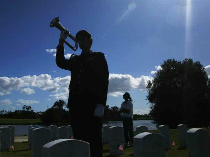 A member of the military plays "Taps" for a family member during a flag ceremony at the South Florida National Cemetery on Veterans Day on Sunday, Nov. 10, 2019, in Lake Worth, Fla. (AP Photo/Brynn Anderson)