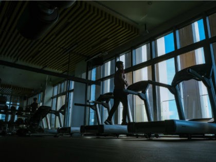 Man running on treadmill in a dark fitness center