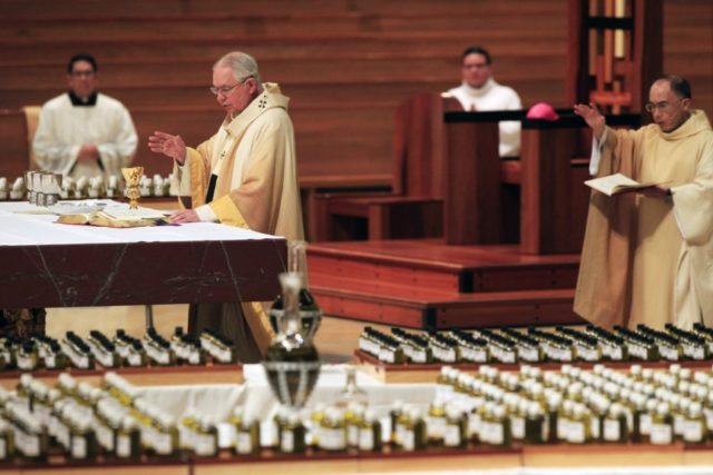 In this April 6, 2020 file photo, Los Angeles Archbishop Jose H. Gomez, front, celebrates the Chrism Mass for the faithful of the nation's largest Catholic Archdiocese in Los Angeles. California says churches can resume in-person services but the congregations will be limited to less than 100 and worshippers should …