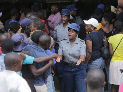 Zimbabwean police control a crowd that had gathered to buy maize meal at a supermarket in