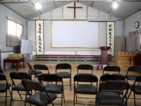 In this photo taken Monday, June 4, 2018, Chinese calligraphy which reads "All nations belong to the Lord arising to shine" at left and "Jesus's salvation spreads to the whole world" at right are displayed below a crucifix in a house church shut down by authorities near the city of …