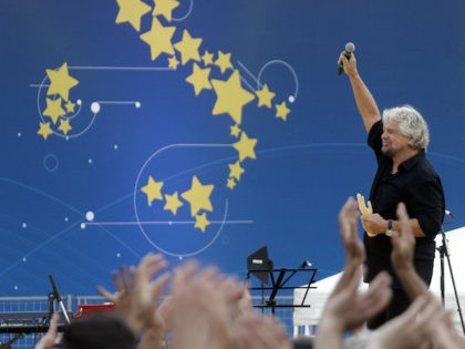 Founder of Five-Star movement Beppe Grillo holds a fake hand as he arrives at a rally at R