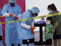 Jerry A. Mann, second from right, stands with his grandmother, Sylvia Rubio, as he prepares to be tested for COVID-19 by the San Antonio Fire Department at a free walk-up test site set up to help underserved and minority communities in San Antonio, Thursday, May 14, 2020. Texas attorney general …