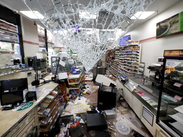 Shattered glass hangs from the doorway of a 7-Eleven store early Sunday morning, May 31, 2