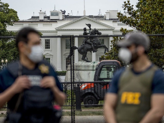 The White House is visible behind a large security fence as uniformed Secret Service and F