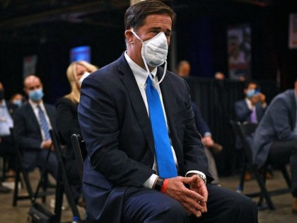 Arizona Governor Doug Ducey (C) listens as US President Donald Trump speaks during a tour