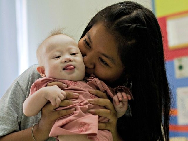 Thai surrogate mother Pattaramon Chanbua (back) plays with her baby Gammy, born with Down Syndrome, at the Samitivej hospital, Sriracha district in Chonburi province on August 4, 2014. The surrogate mother of a baby reportedly abandoned by his Australian parents in Thailand because he has Down Syndrome was a "saint" …