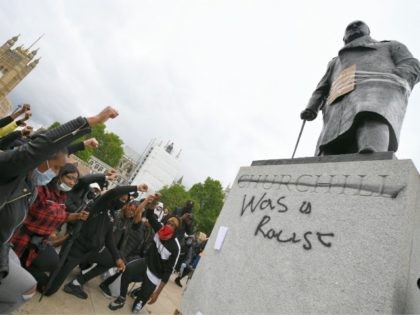 LONDON, UNITED KINGDOM - JUNE 07: Protesters raise their fists in Parliament Square Garden around the statue of Winston Churchill which has graffiti with the words "was a racist" outside the Houses of Parliament in Westminster during a Black Lives Matter protest on June 07, 2020 in London, United Kingdom. …